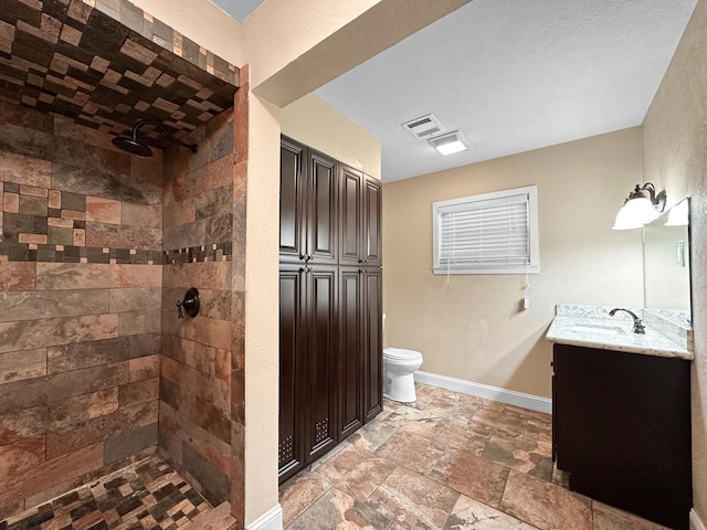 bathroom with toilet, vanity, and tiled shower