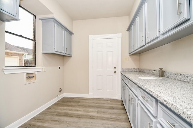 laundry area with electric dryer hookup, light wood-type flooring, washer hookup, cabinets, and sink