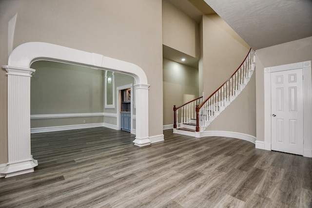 unfurnished living room with dark wood-type flooring and a towering ceiling