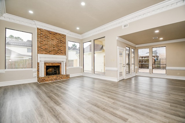 unfurnished living room with a brick fireplace, ornamental molding, and wood-type flooring