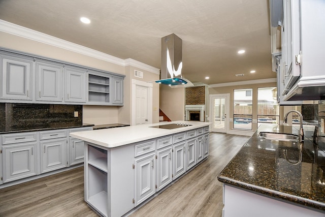 kitchen with a fireplace, gray cabinets, a kitchen island, decorative backsplash, and island exhaust hood