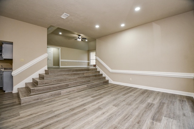 stairs featuring ceiling fan and wood-type flooring