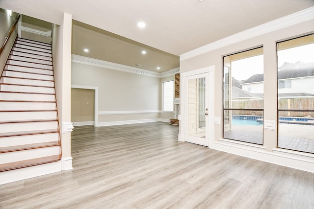 unfurnished living room with plenty of natural light, crown molding, and light hardwood / wood-style floors