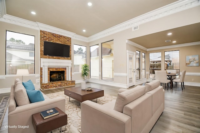 living room featuring light wood-type flooring, ornamental molding, and a fireplace