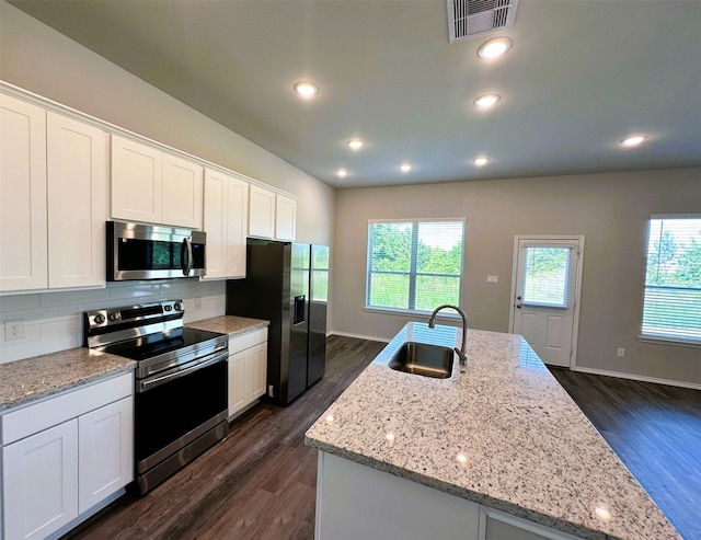 kitchen with white cabinets, stainless steel appliances, an island with sink, and sink