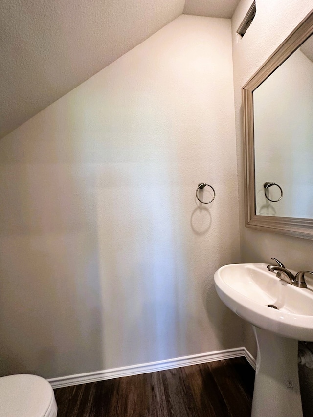 bathroom with toilet, hardwood / wood-style flooring, and vaulted ceiling