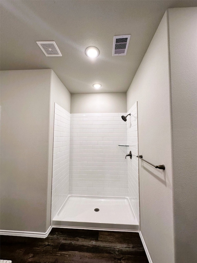 bathroom featuring hardwood / wood-style flooring and a tile shower