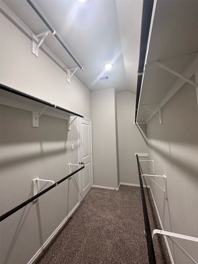 spacious closet featuring lofted ceiling and dark colored carpet