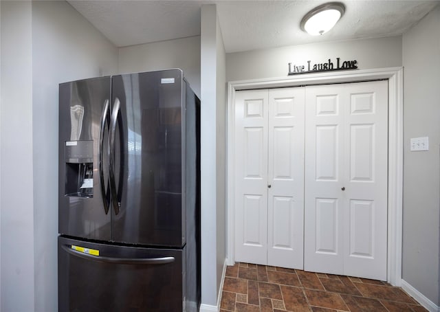 kitchen featuring a textured ceiling and refrigerator with ice dispenser