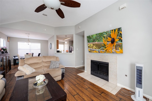 living room featuring ceiling fan, wood-type flooring, heating unit, and a fireplace