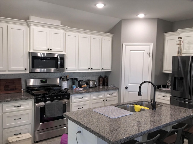 kitchen with white cabinetry, appliances with stainless steel finishes, a kitchen island with sink, and sink