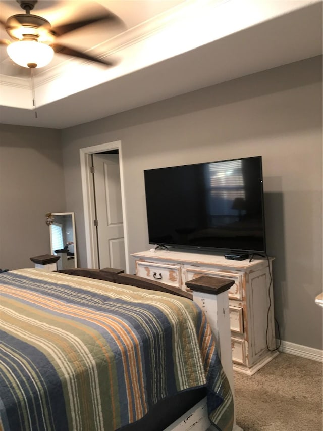 carpeted bedroom featuring a raised ceiling, ornamental molding, and ceiling fan