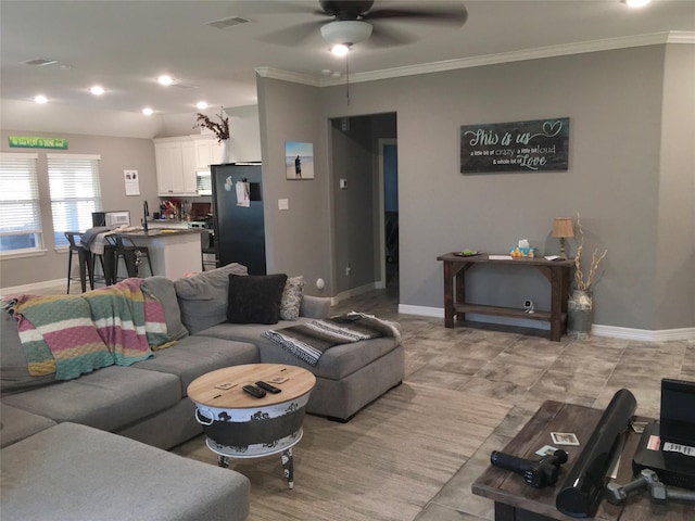 tiled living room with ceiling fan and ornamental molding