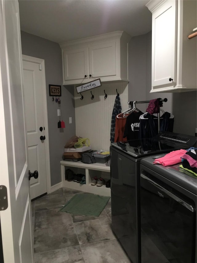 clothes washing area with cabinets and washing machine and dryer