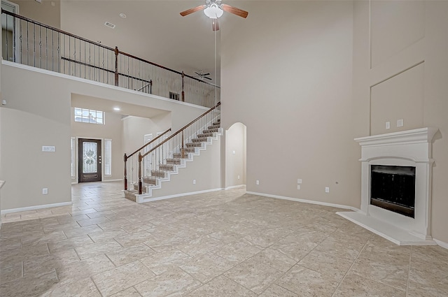 unfurnished living room with a towering ceiling and ceiling fan