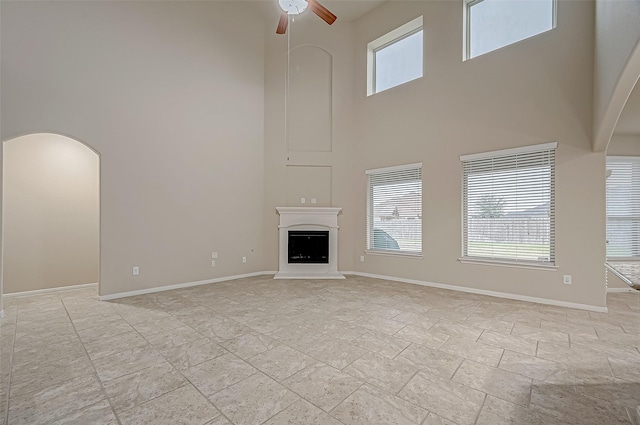 unfurnished living room featuring ceiling fan and a towering ceiling