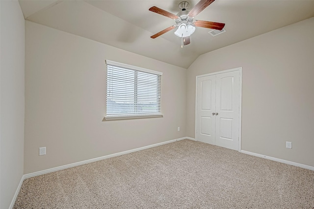 empty room with vaulted ceiling, ceiling fan, and carpet flooring