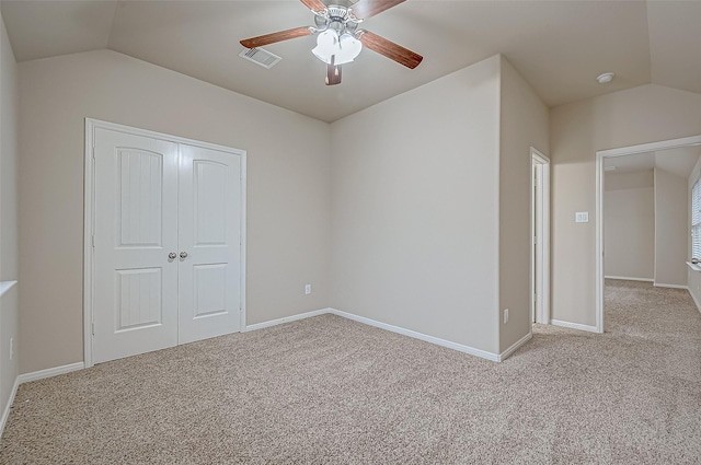 unfurnished bedroom featuring ceiling fan, a closet, light carpet, and lofted ceiling