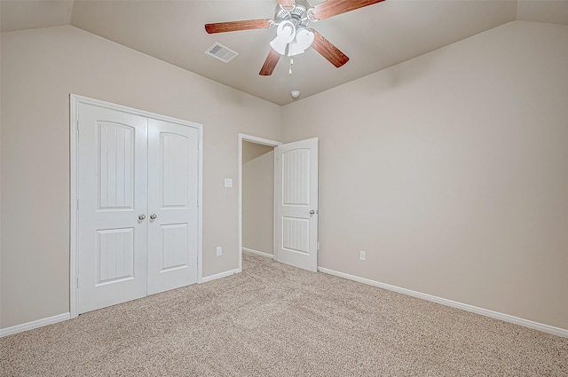 unfurnished bedroom featuring lofted ceiling, light carpet, a closet, and ceiling fan