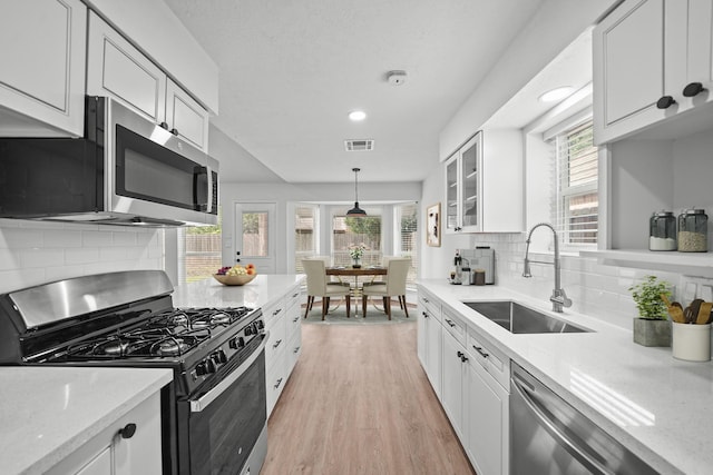 kitchen featuring sink, decorative light fixtures, white cabinets, and appliances with stainless steel finishes