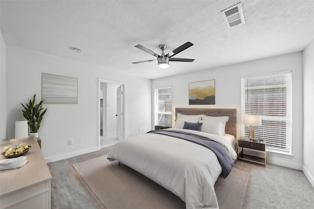 bedroom with ensuite bathroom, carpet floors, ceiling fan, and a textured ceiling