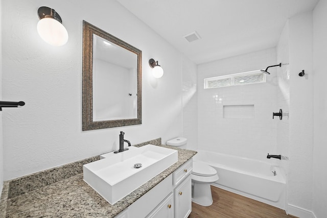 full bathroom featuring toilet, tiled shower / bath combo, vanity, and hardwood / wood-style floors