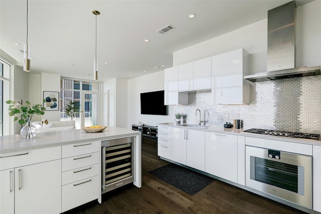 kitchen with sink, oven, decorative light fixtures, stainless steel gas cooktop, and wall chimney exhaust hood