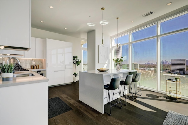 kitchen featuring decorative light fixtures, dark hardwood / wood-style flooring, white cabinets, and decorative backsplash