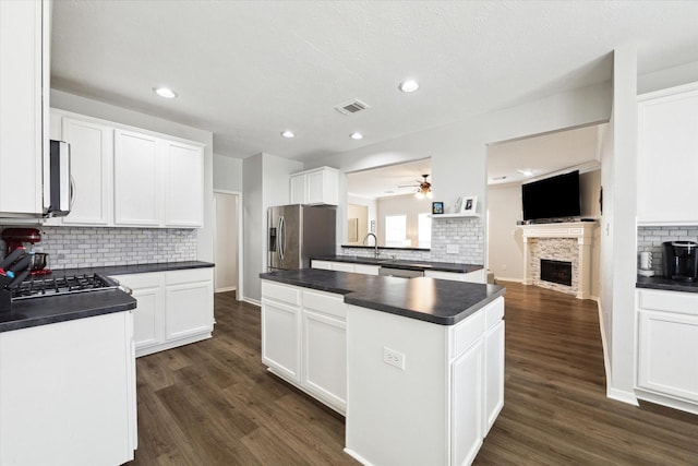 kitchen with stainless steel appliances, white cabinets, a fireplace, and ceiling fan