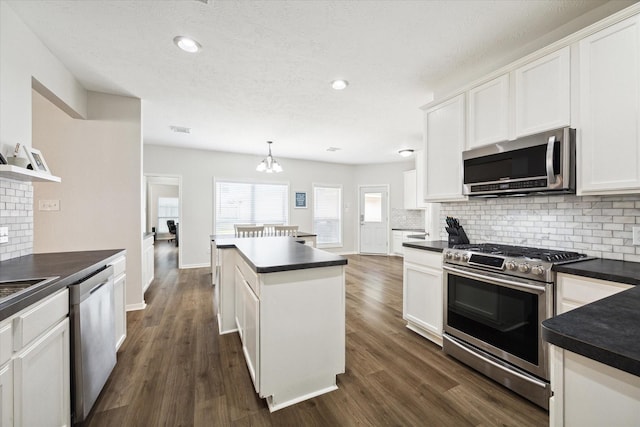 kitchen with white cabinets, dark wood-type flooring, hanging light fixtures, and appliances with stainless steel finishes