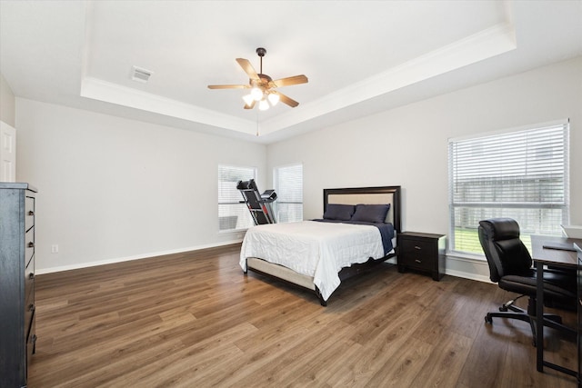 bedroom featuring dark wood-type flooring, a raised ceiling, and ceiling fan