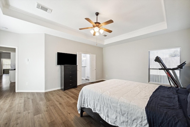 bedroom with a raised ceiling, ceiling fan, and hardwood / wood-style flooring