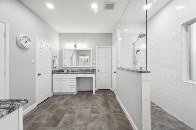 bathroom featuring a tile shower and vanity