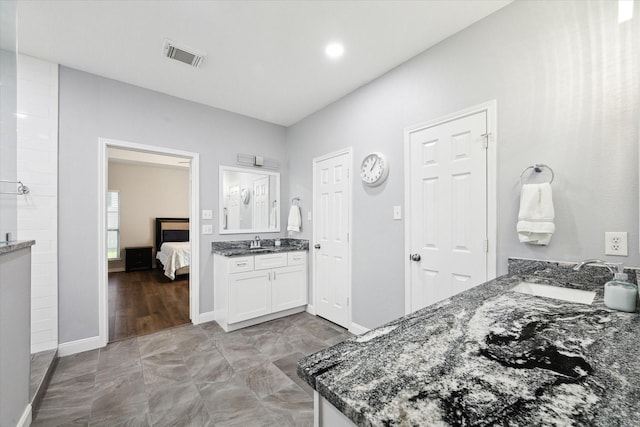 kitchen featuring white cabinets, dark stone countertops, and sink