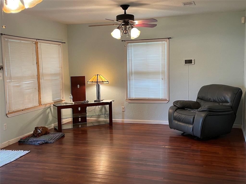 sitting room with ceiling fan and dark wood-type flooring