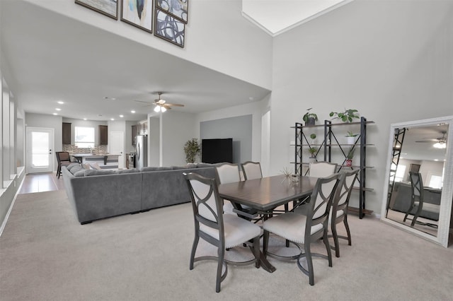 dining space featuring light carpet and ceiling fan