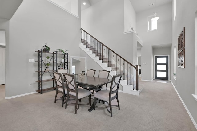 dining room featuring a wealth of natural light, light carpet, and a towering ceiling