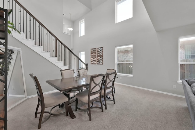 carpeted dining space with a high ceiling