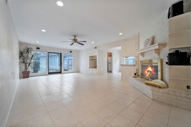 unfurnished living room featuring a fireplace, ceiling fan, and light tile patterned flooring