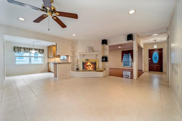 tiled living room featuring a fireplace and ceiling fan