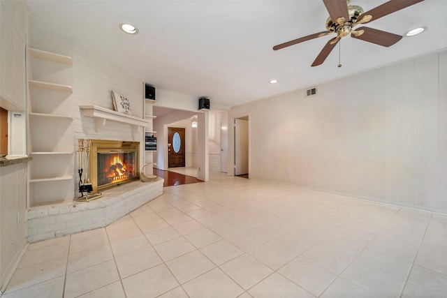 unfurnished living room featuring ceiling fan, light tile patterned flooring, built in features, and a fireplace