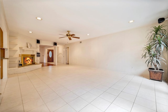 unfurnished living room with built in shelves, ceiling fan, and light tile patterned floors