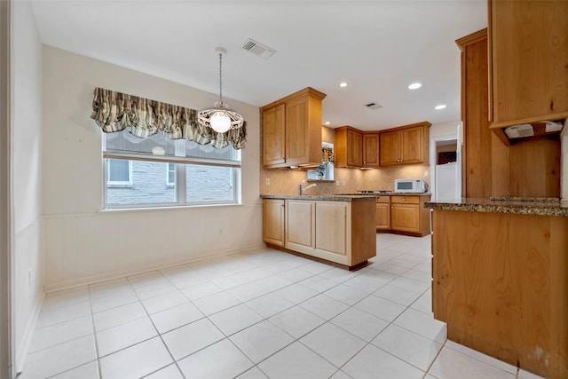 kitchen with sink, stone countertops, light tile patterned floors, and backsplash