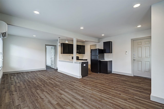 kitchen featuring black appliances, dark hardwood / wood-style flooring, a wall mounted AC, and sink