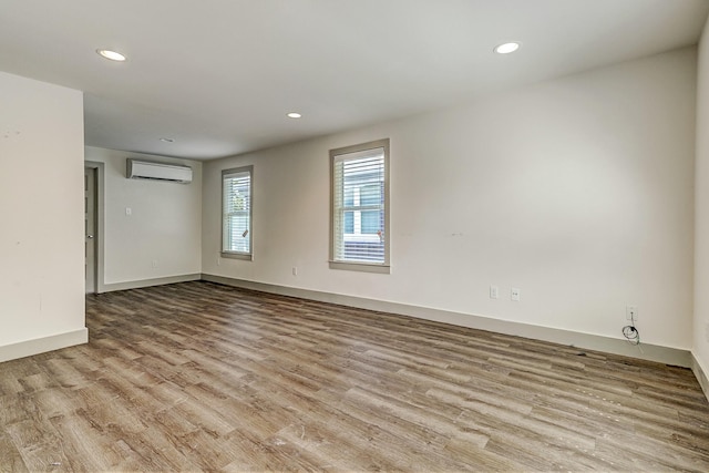 unfurnished room with light wood-type flooring and a wall unit AC