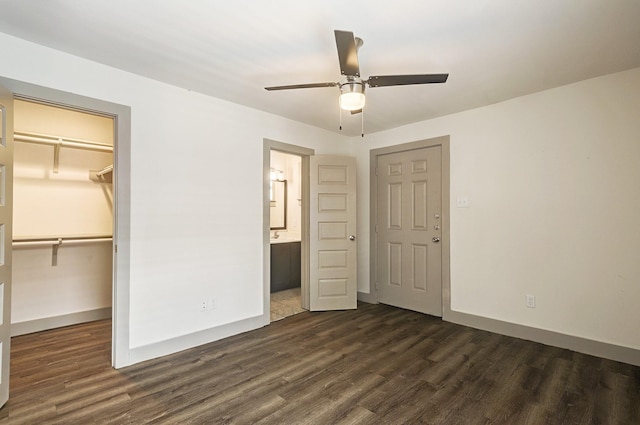 unfurnished bedroom with ensuite bath, ceiling fan, a closet, a walk in closet, and dark hardwood / wood-style flooring