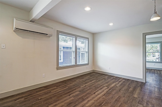 unfurnished room with a wall mounted air conditioner, dark hardwood / wood-style flooring, and beamed ceiling