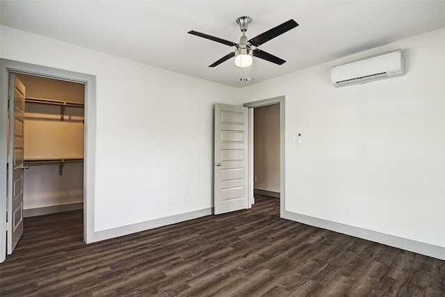 unfurnished bedroom featuring a wall mounted AC, a spacious closet, dark hardwood / wood-style floors, a closet, and ceiling fan