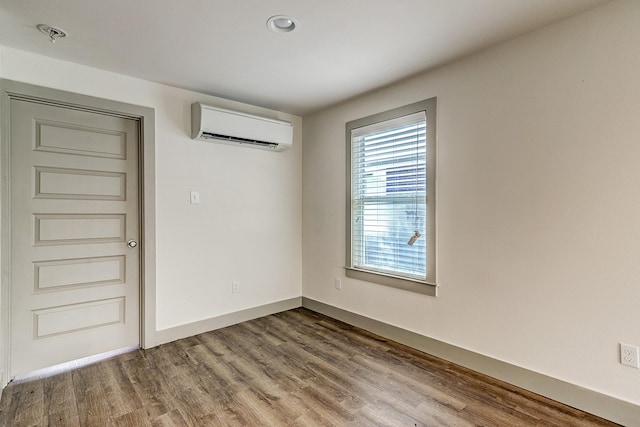 unfurnished room with a wall mounted air conditioner and hardwood / wood-style flooring