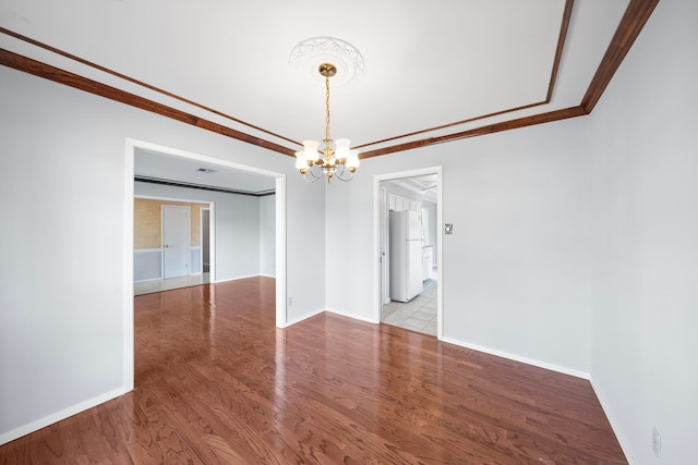 spare room with an inviting chandelier, crown molding, and light wood-type flooring